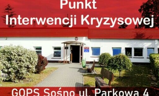 Biały napis punkt informacji kryzysowej na czerwonych paskach w tle budynek GOPS w Sośnie