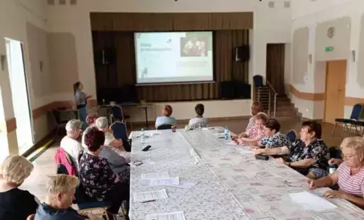 starsza osoba dekorująca ozdobę pisakiem. Zdjęcie wykonano za pleców artystki widoczne są średniej długości blond włosy i okulary.